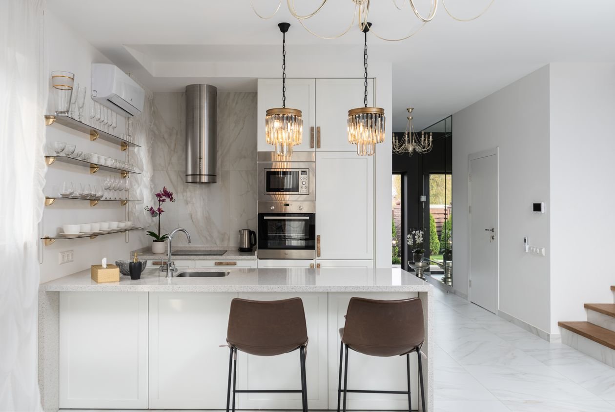 Cocina moderna con armarios blancos, encimera clara e iluminación elegante